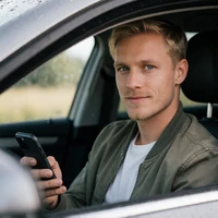 Jonas M., mobiler Spieler bei Millioner Casino, mit Smartphone im Auto